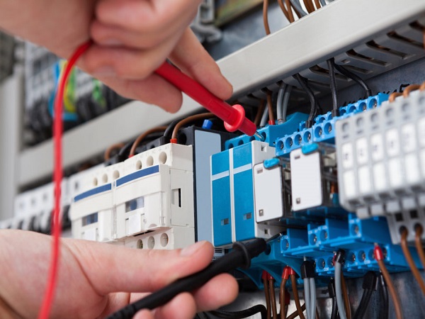 Electrician Examining Fusebox With Multimeter Probe